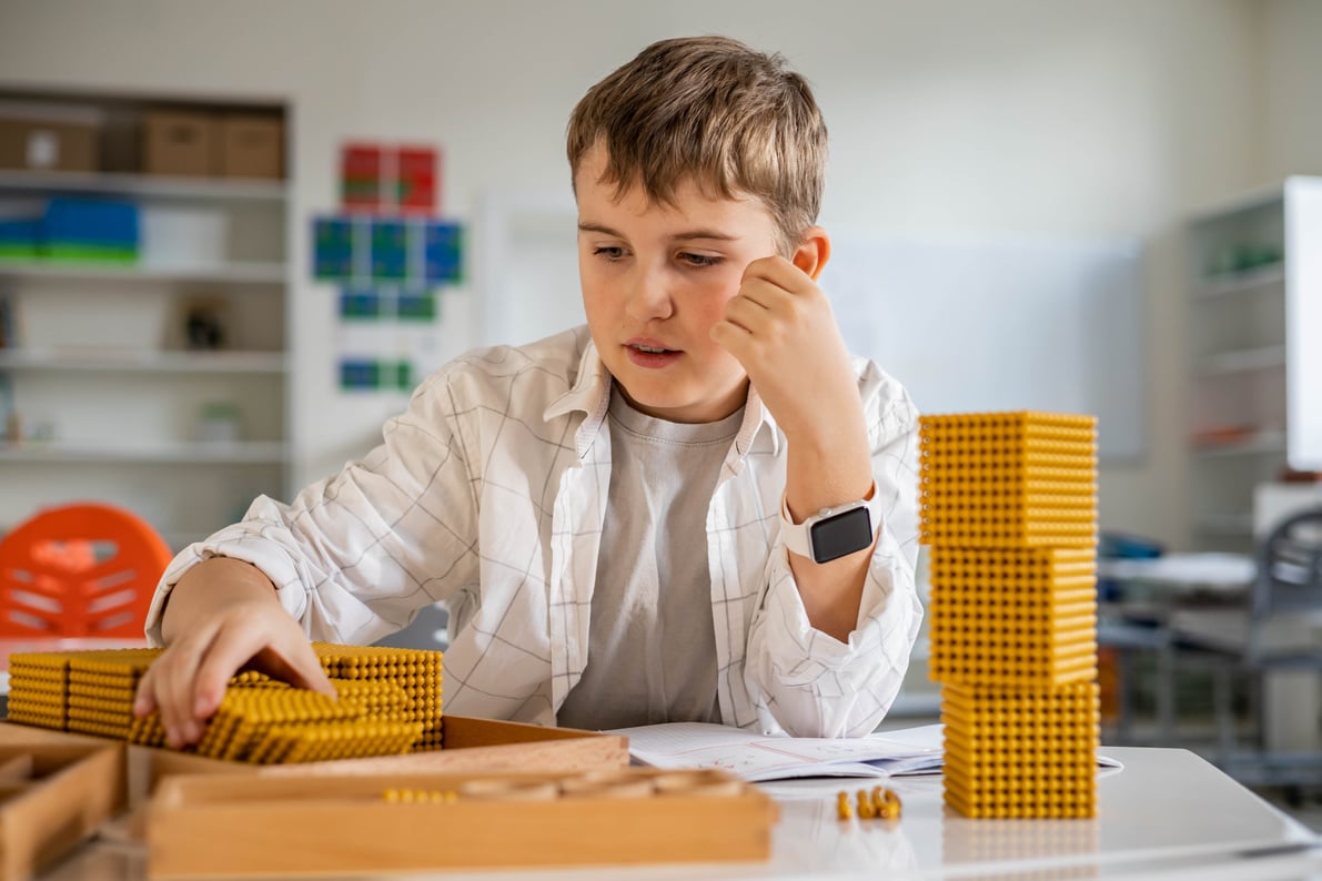 Smiling male kid with Montessori math golden bank material beads alternative counting development